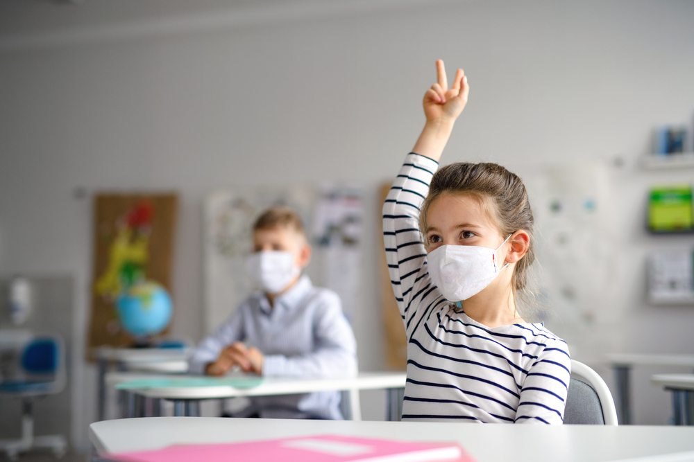 Child wearing an N95 mask in an elementary school class. Showing COVID safety protocols in schools. 