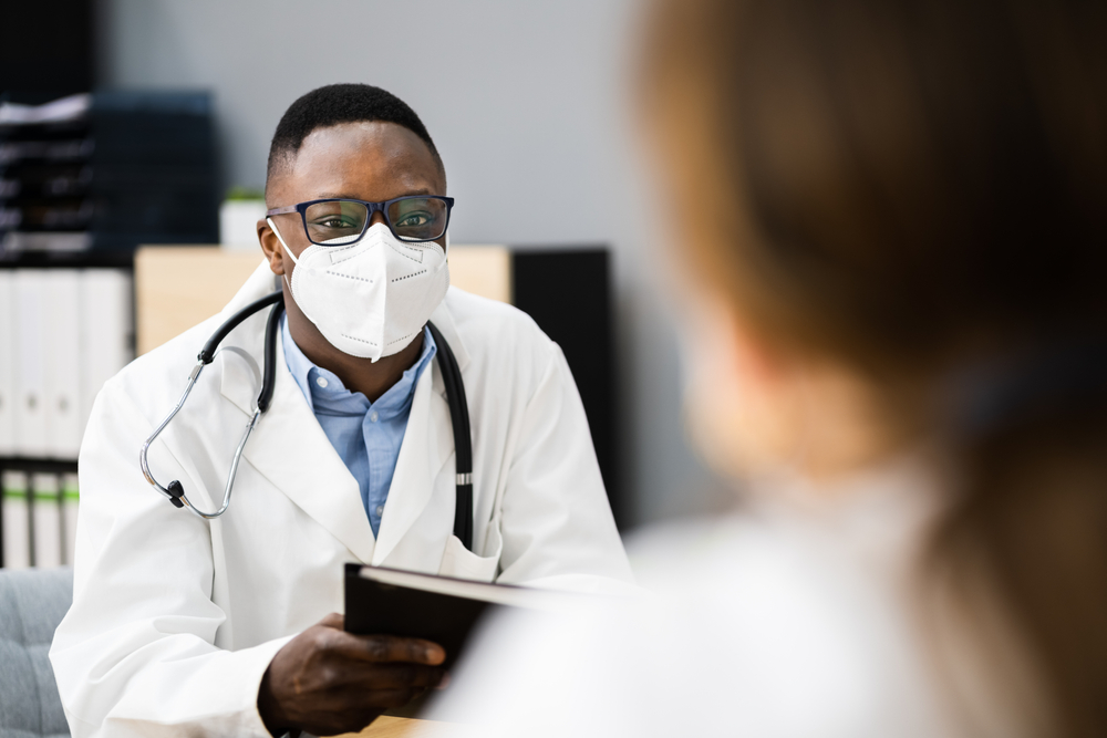 Doctor meeting with patient while wearing an N95 face-covering to prevent spread of COVID-19 and other illnesses